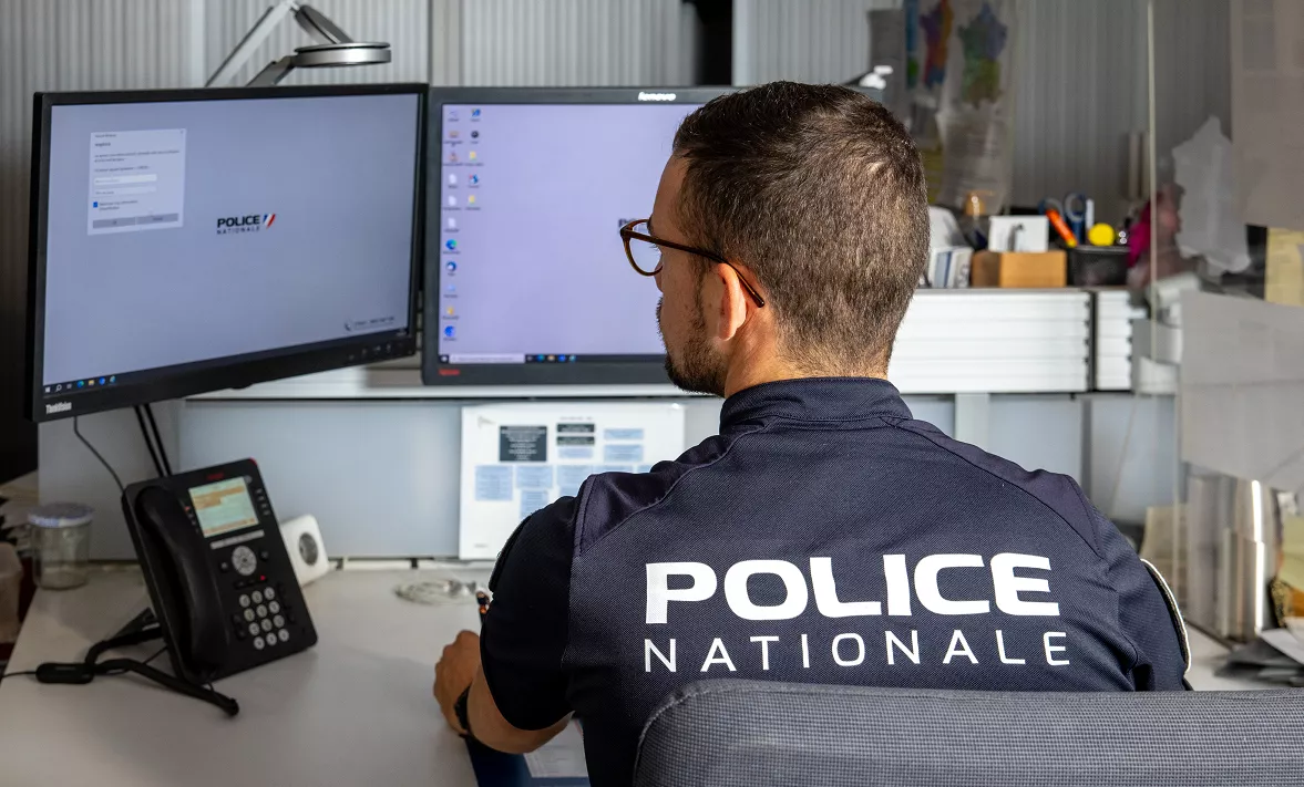 Policier de dos devant un écran d'ordinateur